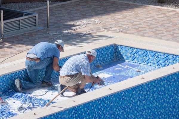 Two men working on swimming pool on the residential building courtyard. Preparing for summer - Mahmutlar, Alanya, Turkey - May 18, 2021