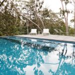 Stunning blue tiled infinity swimming pool in Australian home with bush garden setting