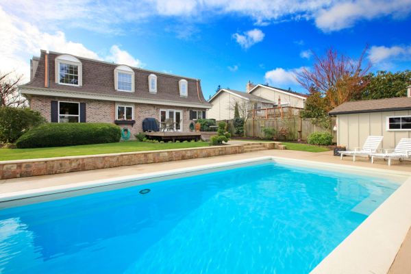 Two story stone facing house with back porch and big swimming pool