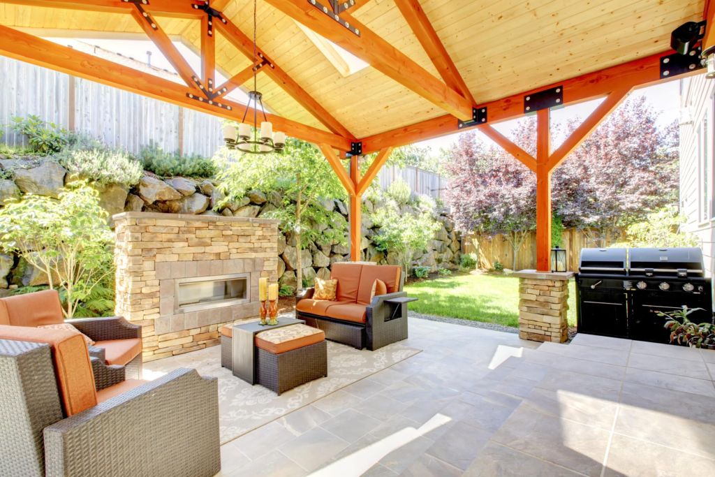 Exterior covered patio with fireplace and furniture. Wood ceiling with skylights.