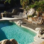 Retro Sun bed on the edge of a blue swimming pool in the rocks, of the concept of travel, selective focus