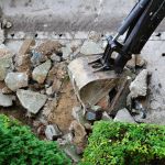 Excavator breaks and removes old concrete sidewalk. Sidewalk reconstruction
