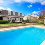 Two story stone facing house with back porch and big swimming pool