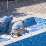 Two men working on swimming pool on the residential building courtyard. Preparing for summer - Mahmutlar, Alanya, Turkey - May 18, 2021